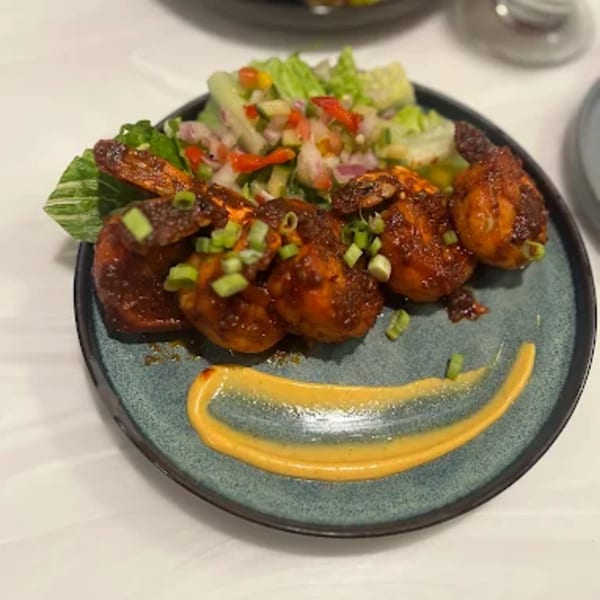 Spicy shrimp with green onions and a side salad, garnished with a yellow sauce smile.